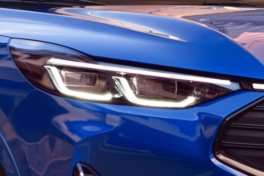 A close up of the front headlight of a blue Ford Kuga.