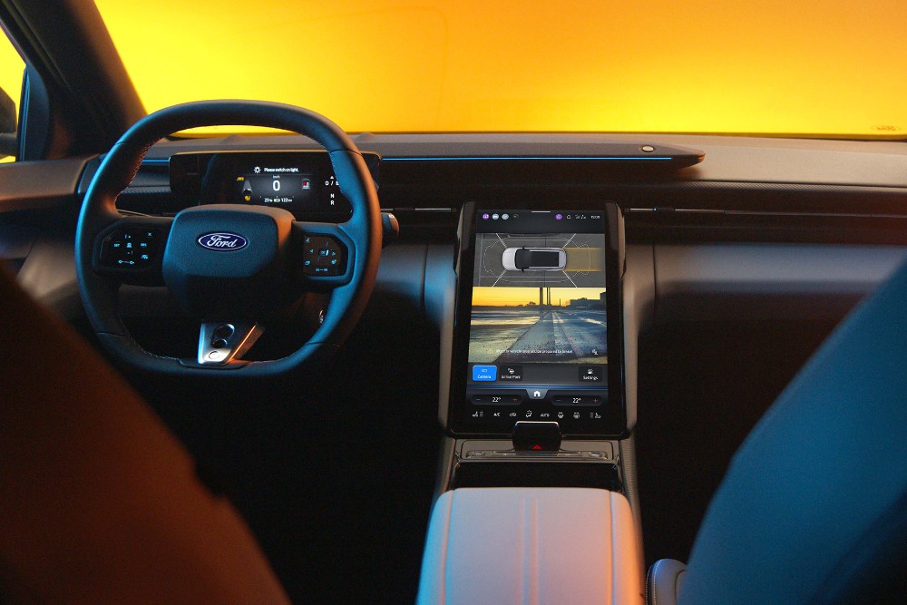 The interior of the all-electric Ford Capri showing the steering wheel and SYNC Move touchscreen.