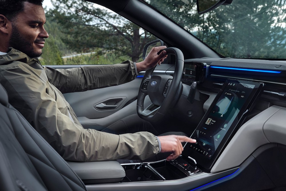 A man sitting in the driving seat of the Ford Explorer, interacting with the large SYNC touchscreen.