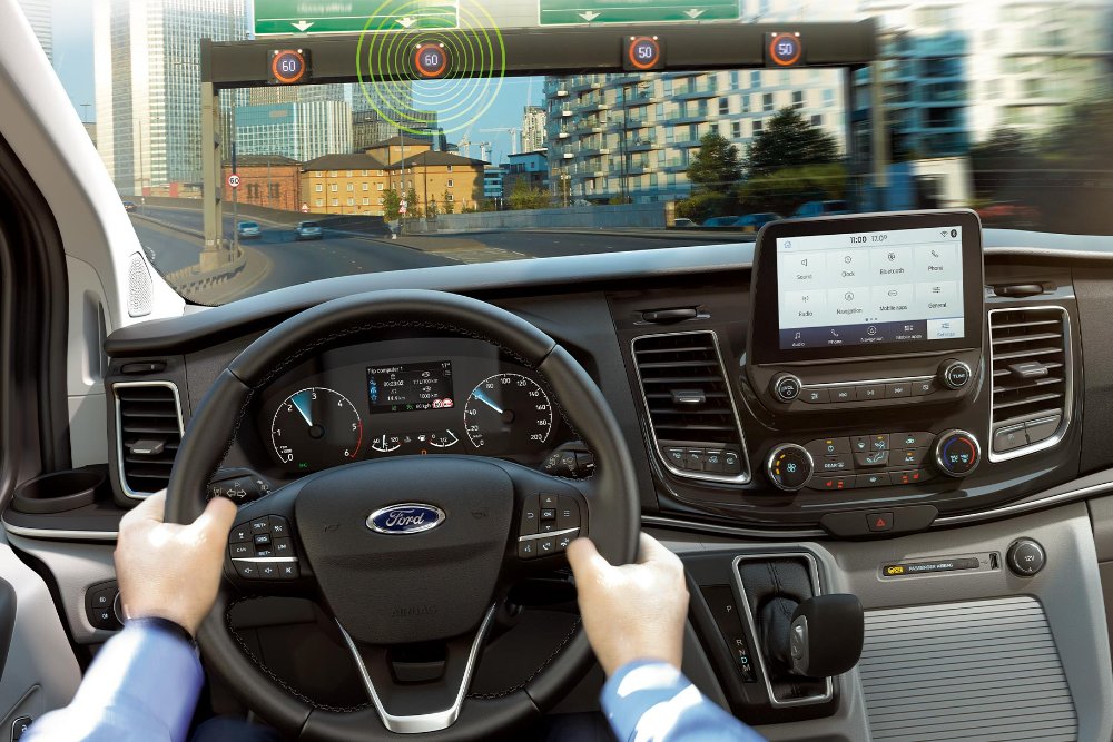 Ford interior view. Hands on the steering wheel of a Ford vehicle driving in an urban area