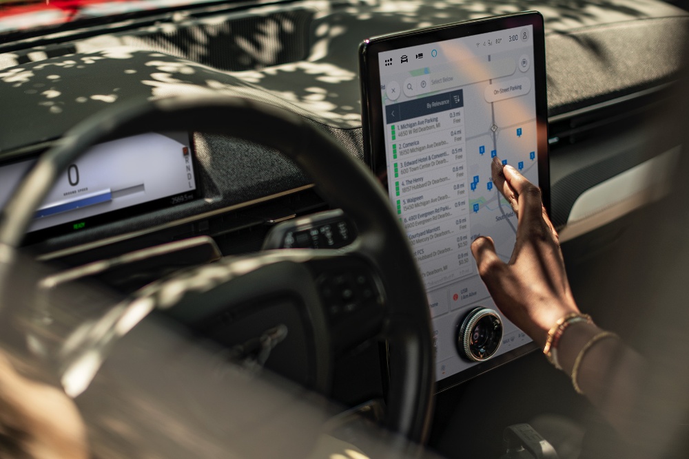 A close up of a woman in a Ford Mustang Mach-E interacting with the large SYNC touchscreen.