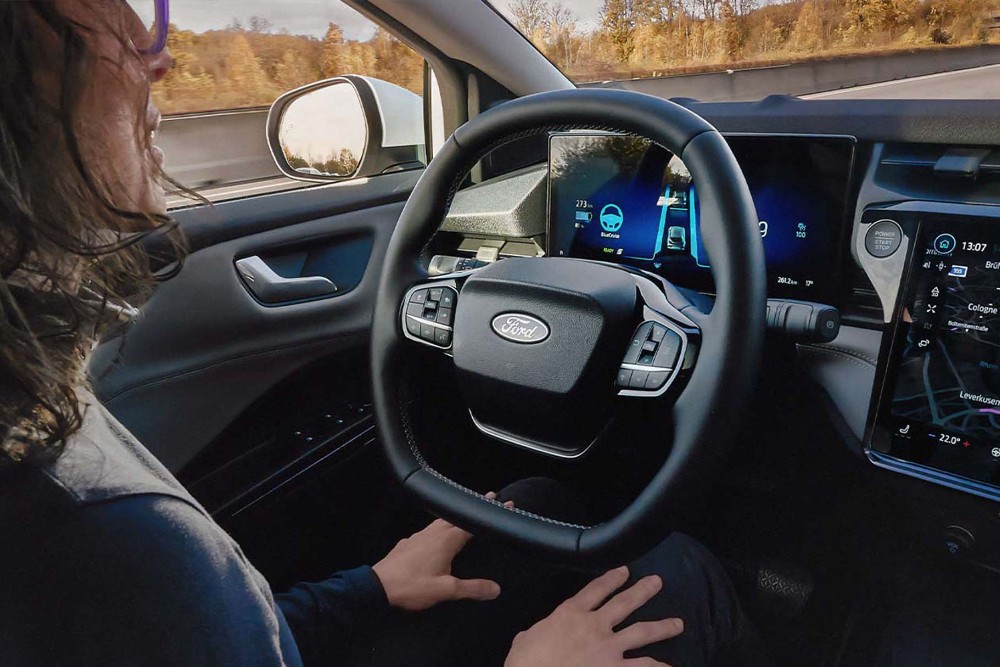 A man sitting in the Ford Mustang Mach-E with his hands away from the steering wheel, showing the BlueCruise technology.