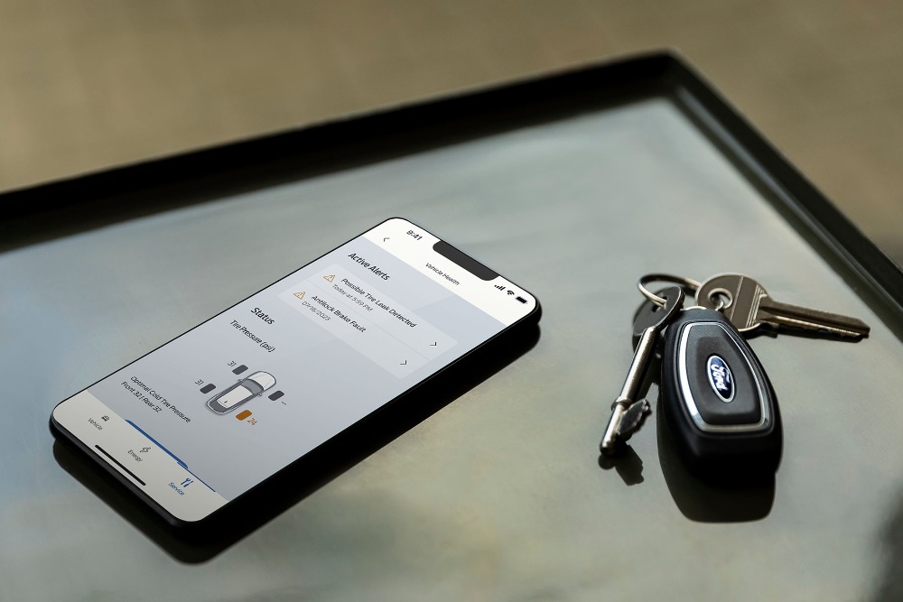 A phone displaying FordPass next to Ford car keys