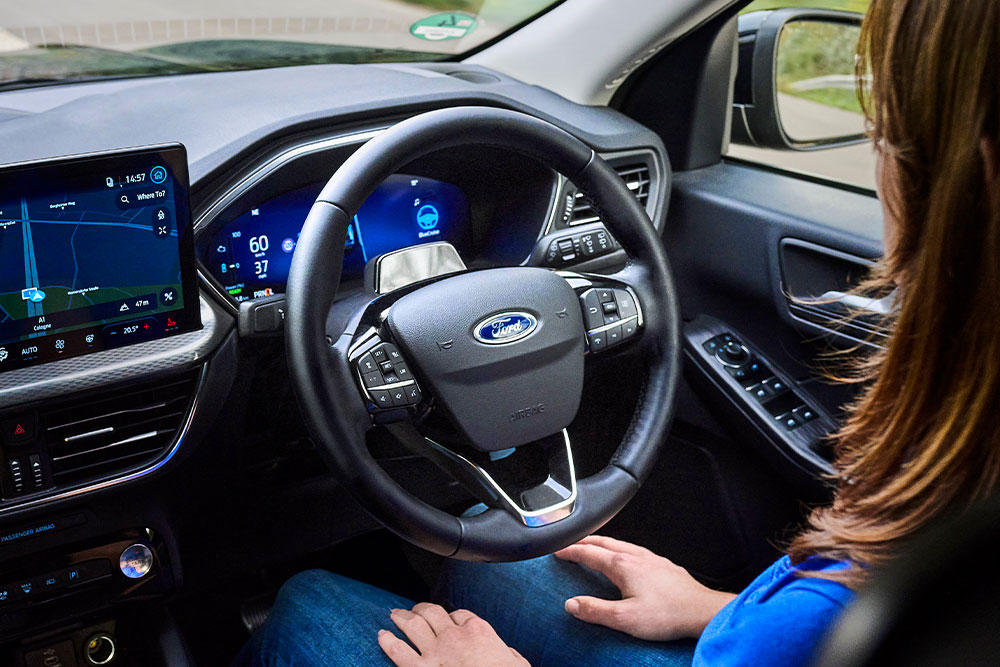 A person sitting in the Ford Kuga with their hands away from the steering wheel, showing the BlueCruise technology.