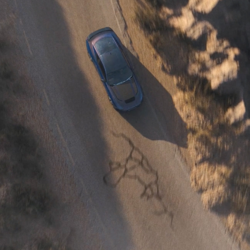 An overhead photo of a Ford Mustang Dark Horse Fastback in Blue Ember paint driving along a mountain road.