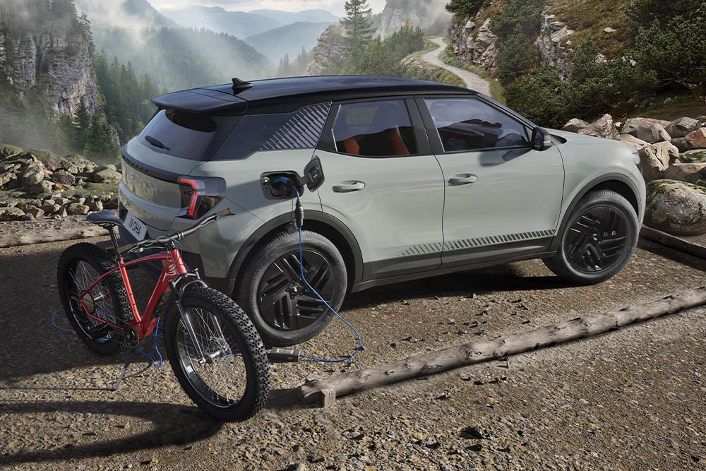 An e-bike charging from a Ford Explorer®, mountainous landscape in the background.