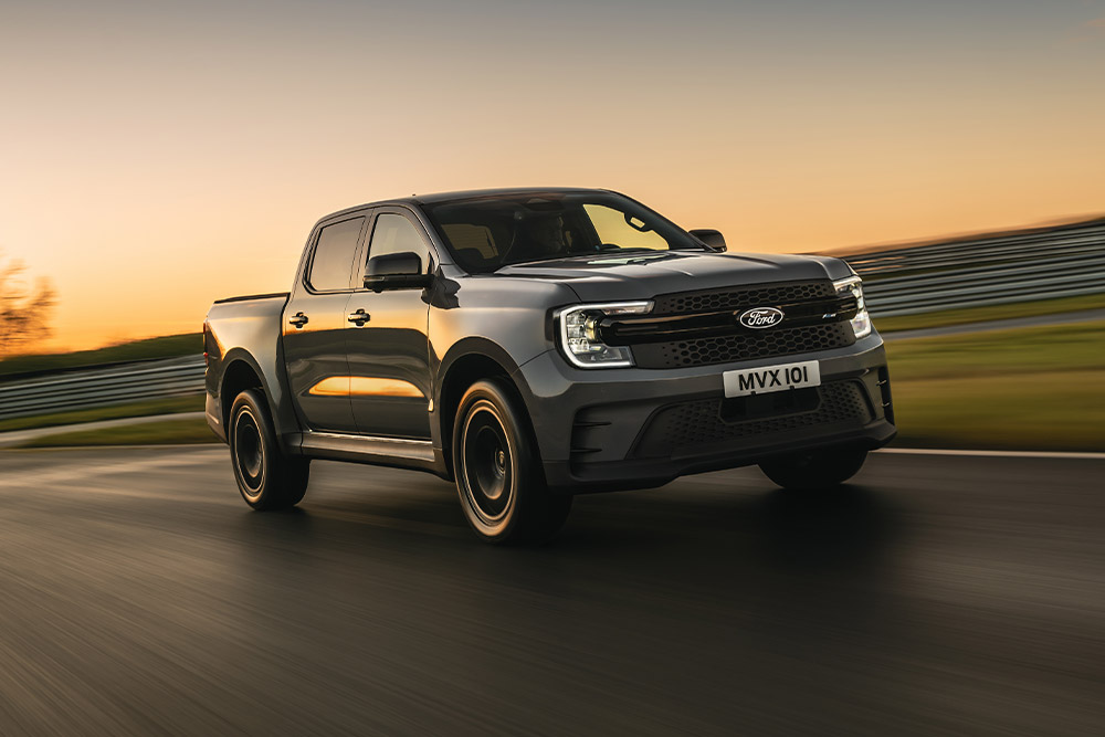 A dark gray Ford Ranger Platinum drives on a track at sunset.