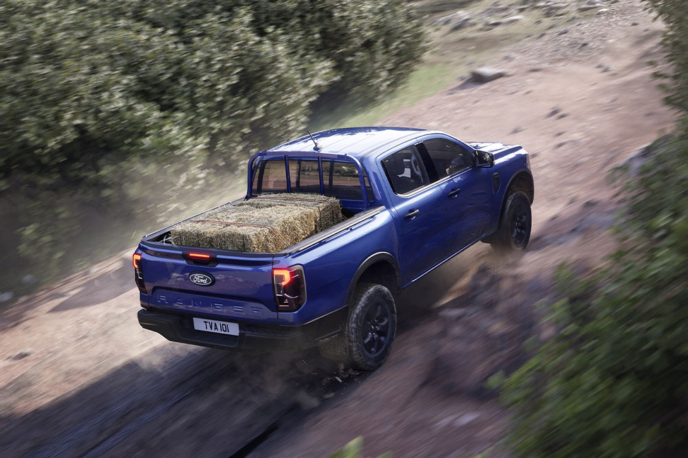 Top rear view of a blue Ford Ranger driving along a dirt road.