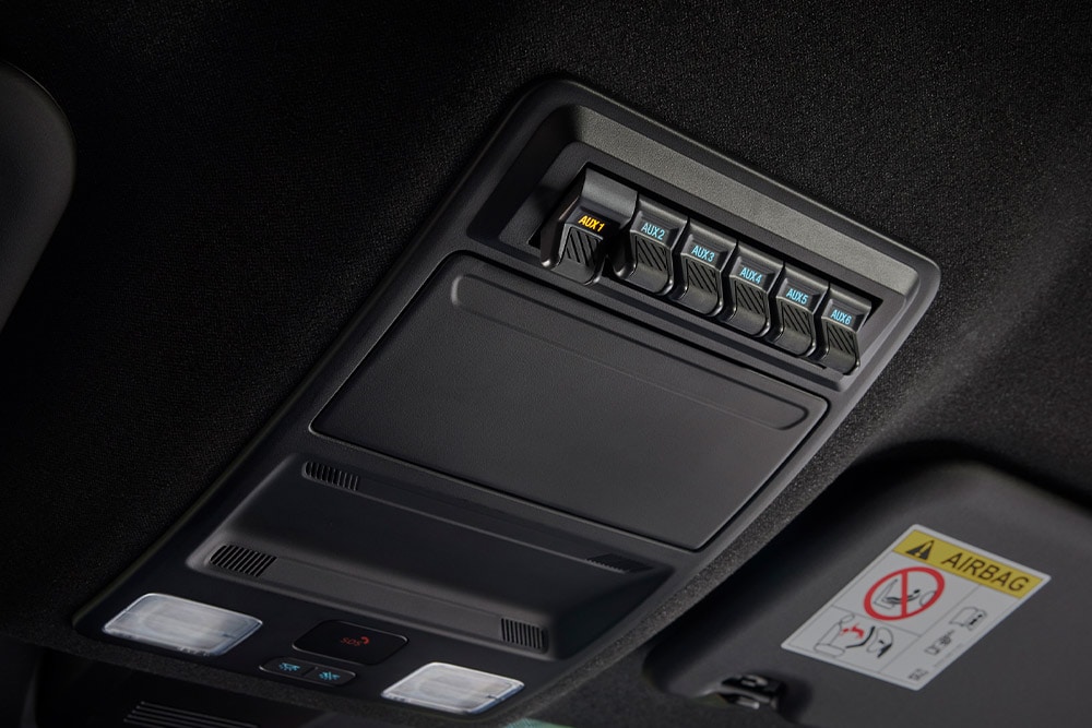 Close-up of hands connecting cables to the power outlet in the truck bed of the Ford Ranger.