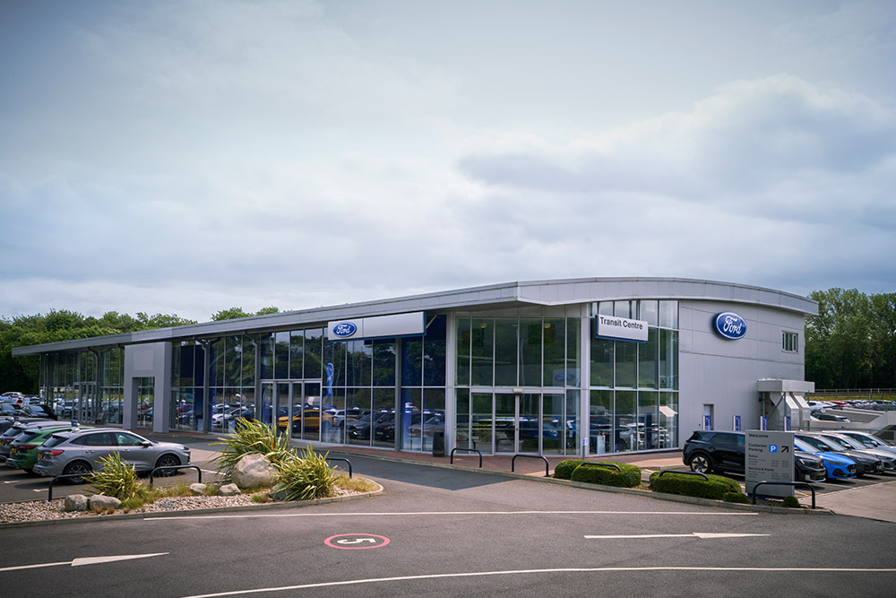 Exterior view of a modern Ford dealership building with various Ford vehicles parked outside.