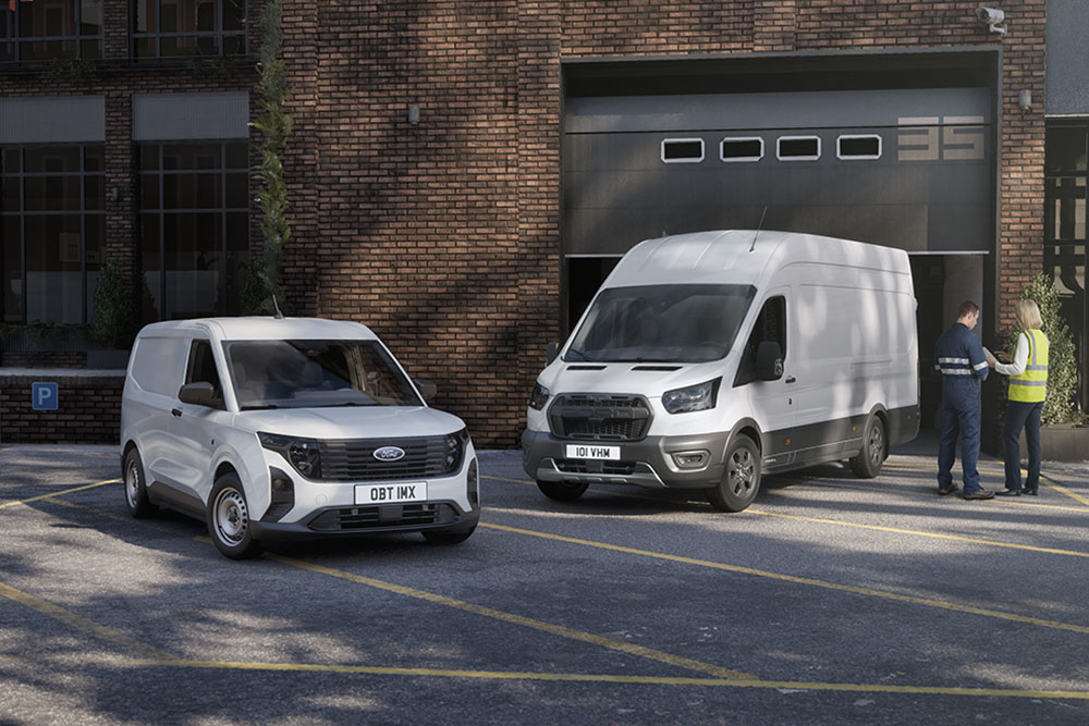 Two white Ford Transit vans parked in front of a modern building, two people chatting next to the vehicles.