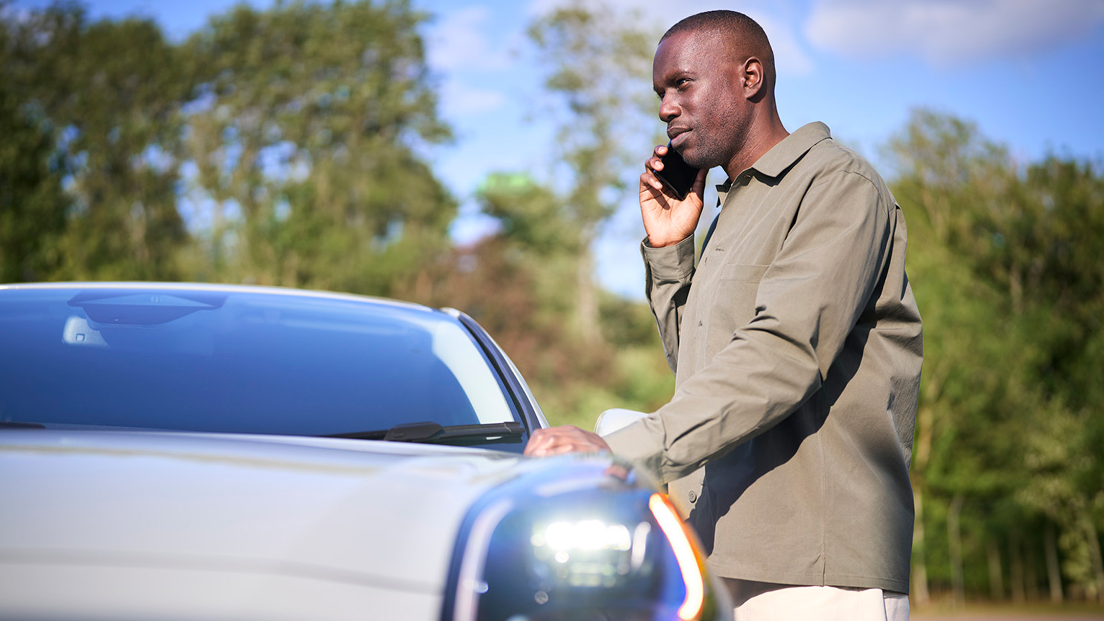 A person places a red warning triangle by a car that has broken down at the side of a road.