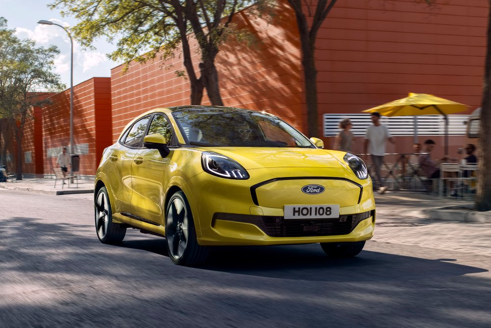 A yellow Ford Puma driving on a city street, with people in the background.