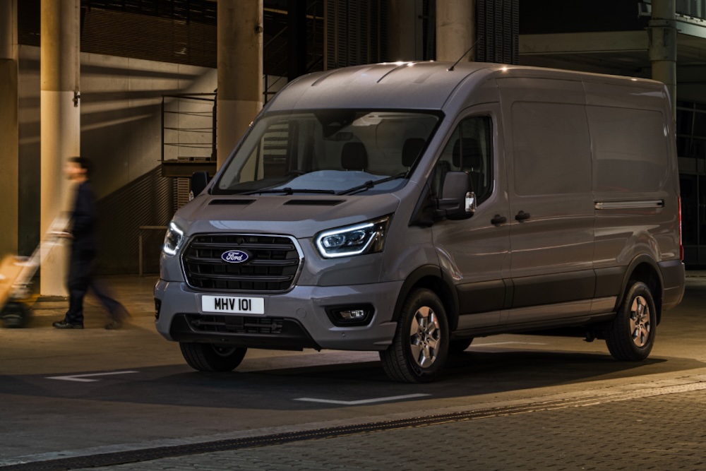 Grey Ford Transit van parked at night in an urban setting.