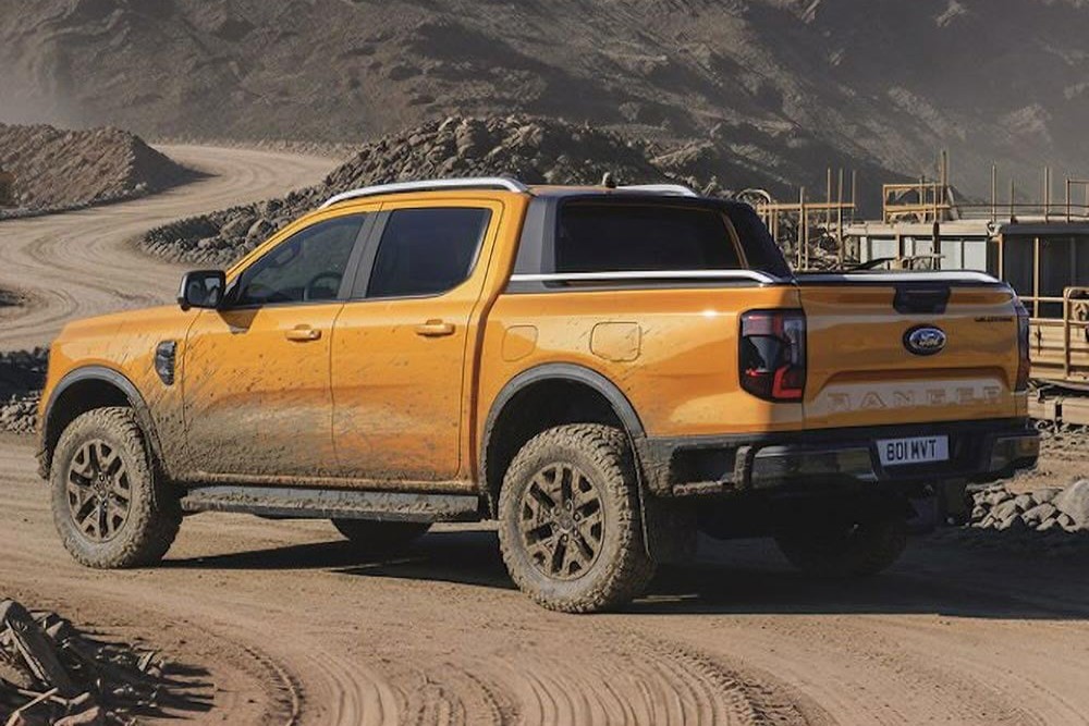 Orange Ford Ranger pickup truck on a dirt road at a construction site.