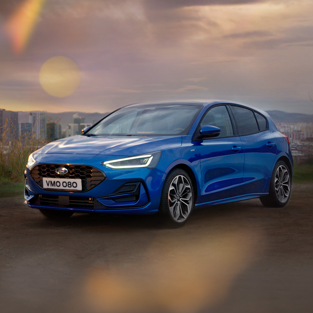 A blue Ford Focus parked on a bridge, with the five-star Euro NCAP safety rating badge in the bottom right corner.